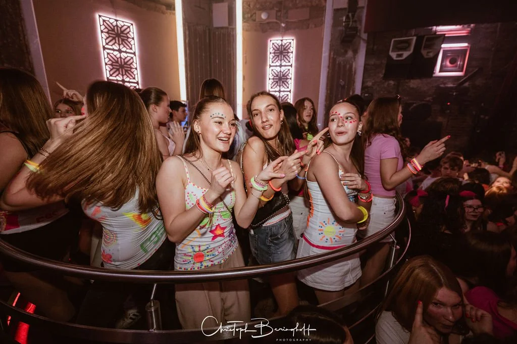 Teenagers are partying at a disco with body paint and neon lights.