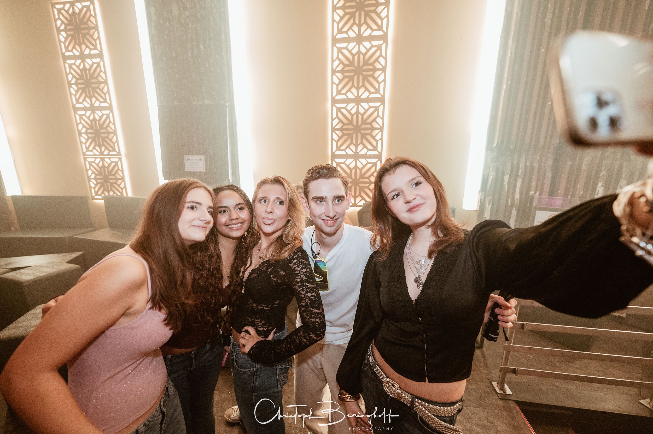 Eine Gruppe junger Menschen macht ein Selfie in einem modernen, gut beleuchteten Raum.