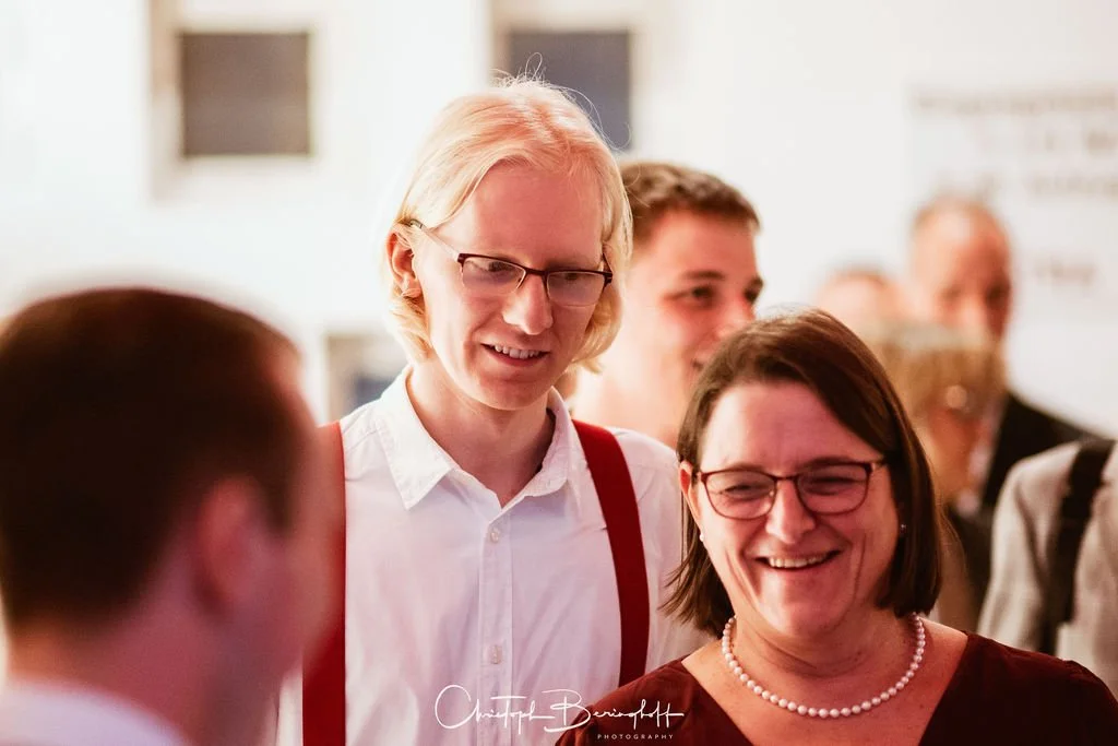 Menschen bei einer gesellschaftlichen Veranstaltung, lachend und im Gespräch.