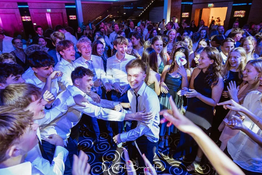 Junge Leute feiern auf einer Party, tanzen und lachen im festlich dekorierten Raum.