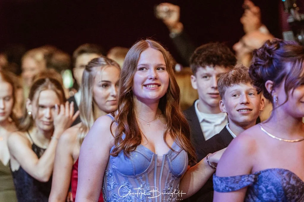 Junge Menschen in formeller Kleidung auf einer Party oder Feier, Lächeln und Applaus, festliche Atmosphäre.