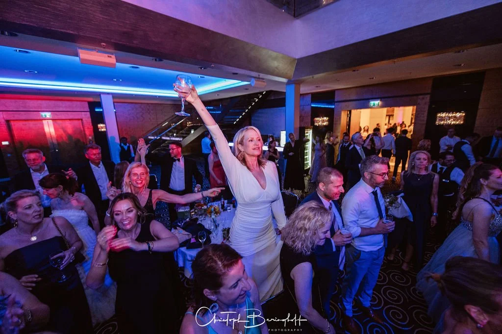 Menschen feiern auf einer Party im eleganten Veranstaltungsraum, einige tanzen und einige halten Getränke in der Hand.