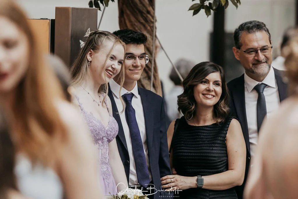 Gruppe von Menschen bei einer Feier, vermutlich Hochzeit, lachend und im Gespräch.
