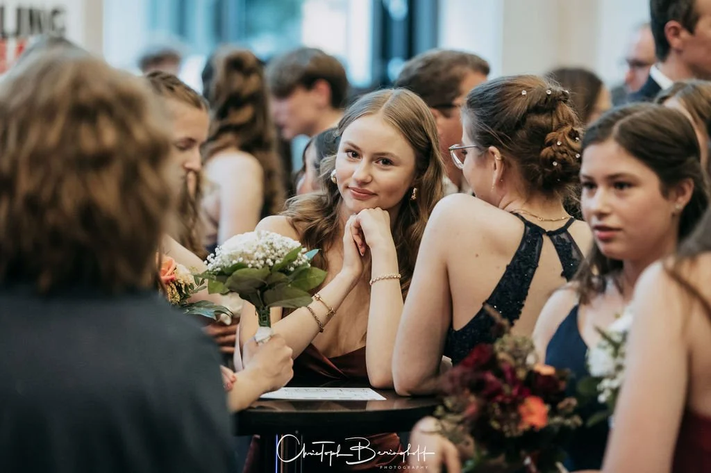 Gruppe junger Frauen und Mädchen in eleganten Kleidern bei einer festlichen Veranstaltung