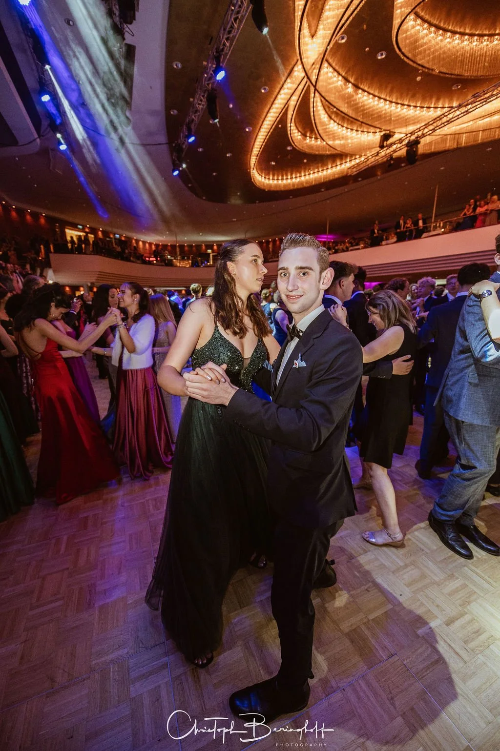 Paare tanzen in Abendgarderobe in einem eleganten Ballsaal bei einer formellen Veranstaltung.