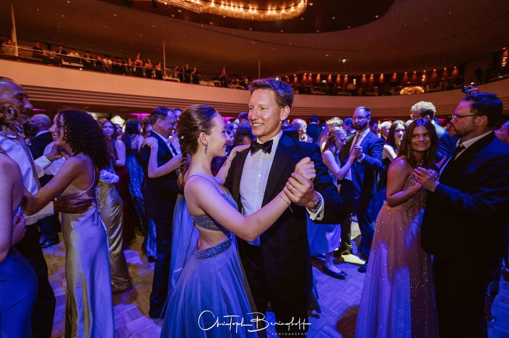 Menschen tanzen bei einer formellen Gala in einem eleganten Saal.