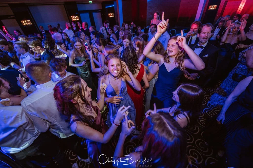 Menschen tanzen und feiern auf einer Party in einem festlich beleuchteten Raum.