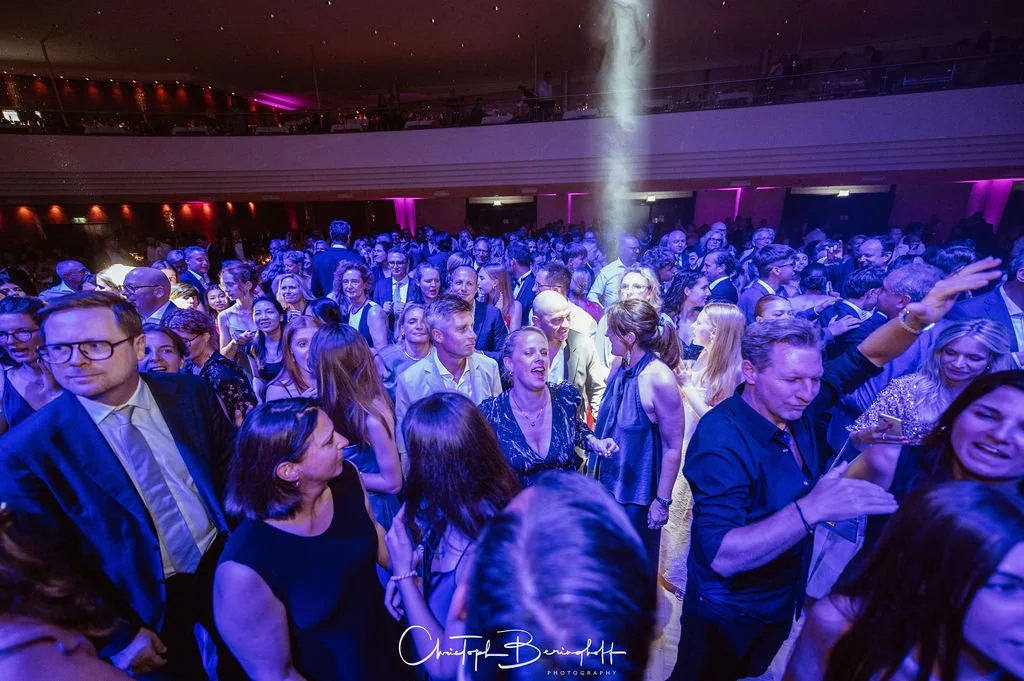 Menschen tanzen und feiern in einer großen Halle bei einer Party mit buntem Licht