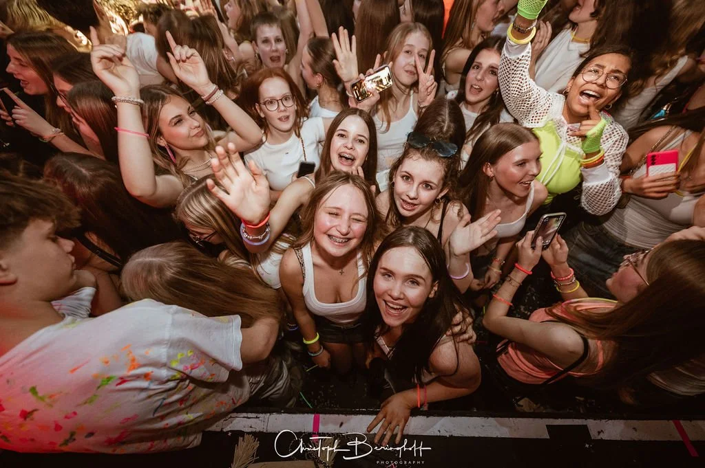 Young people are partying, laughing, posing for photos, and making peace signs.