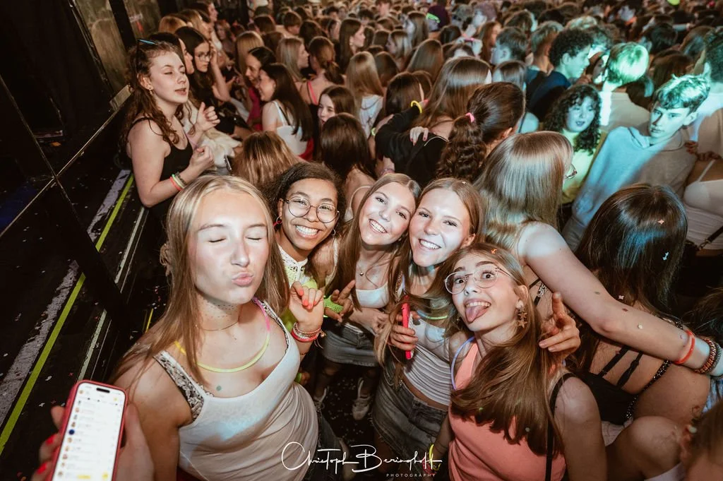 Young girls at a concert, having fun and taking photos.