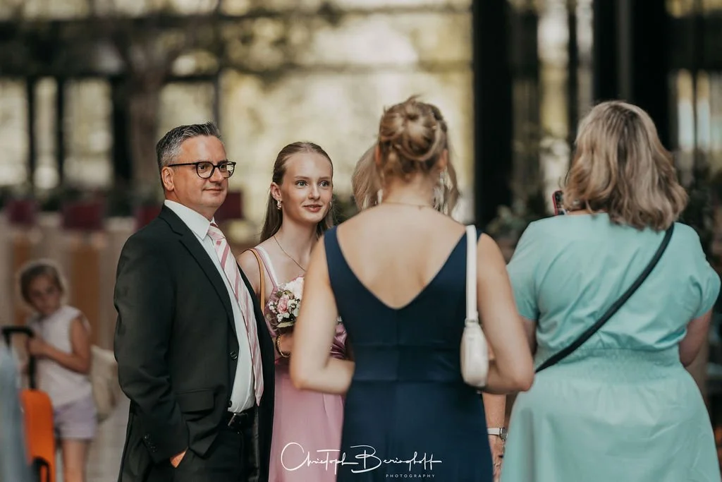 Menschen sprechen auf einer Hochzeit, im Hintergrund Kinder sitzen.