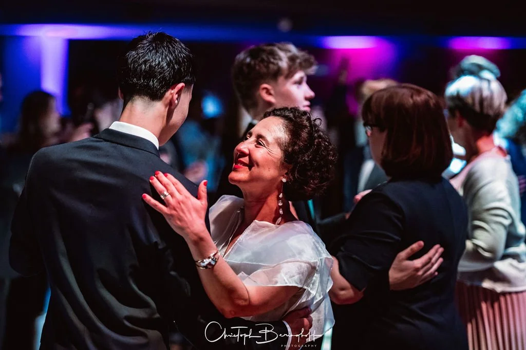 Menschen tanzen und lachen auf einer Party mit bunten Lichteffekten.
