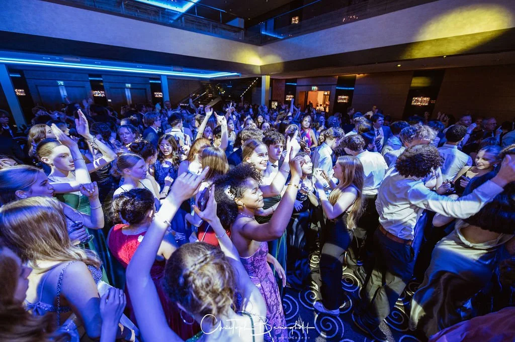 Junge Menschen tanzen und feiern auf einer Party im dunklen Raum mit buntem Licht.