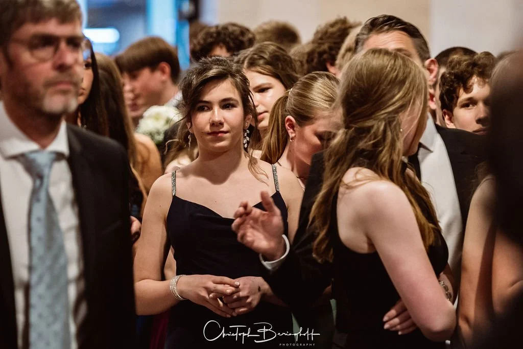 Menschen bei einem formellen Event, die meisten in eleganter Kleidung, in einem festlichen Raum.