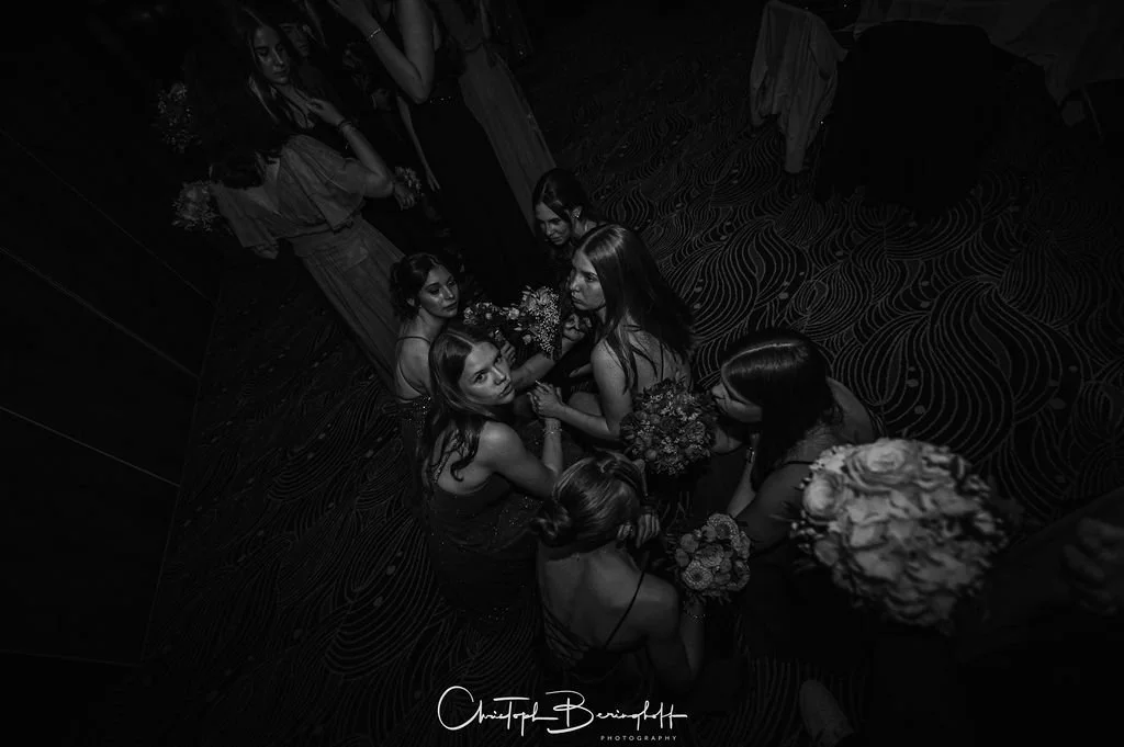 Mehrere Frauen auf einer Party, die Blumen halten, im Schwarz-Weiß-Foto.
