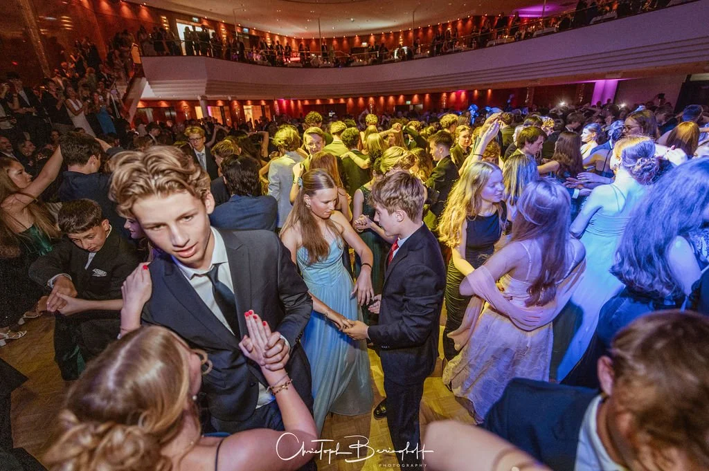 Menschen tanzen und feiern auf einer bunten Tanzfläche bei einer Party oder Ball im festlichen Ambiente.