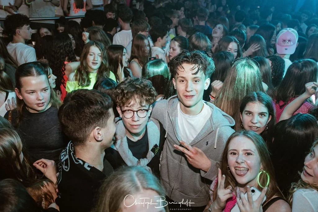 A group of young people are partying; many are laughing and taking photos.