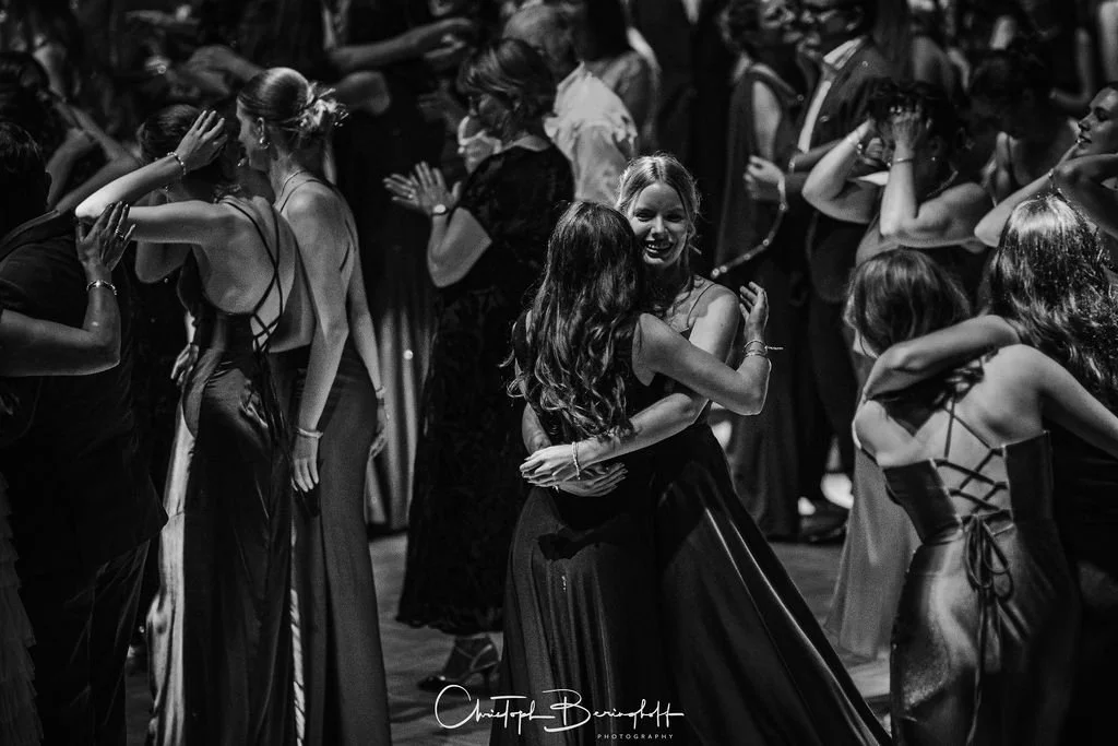 Menschen tanzen auf einer Party, einige umarmten sich, trugen elegante Kleidung, in schwarz-weiß.