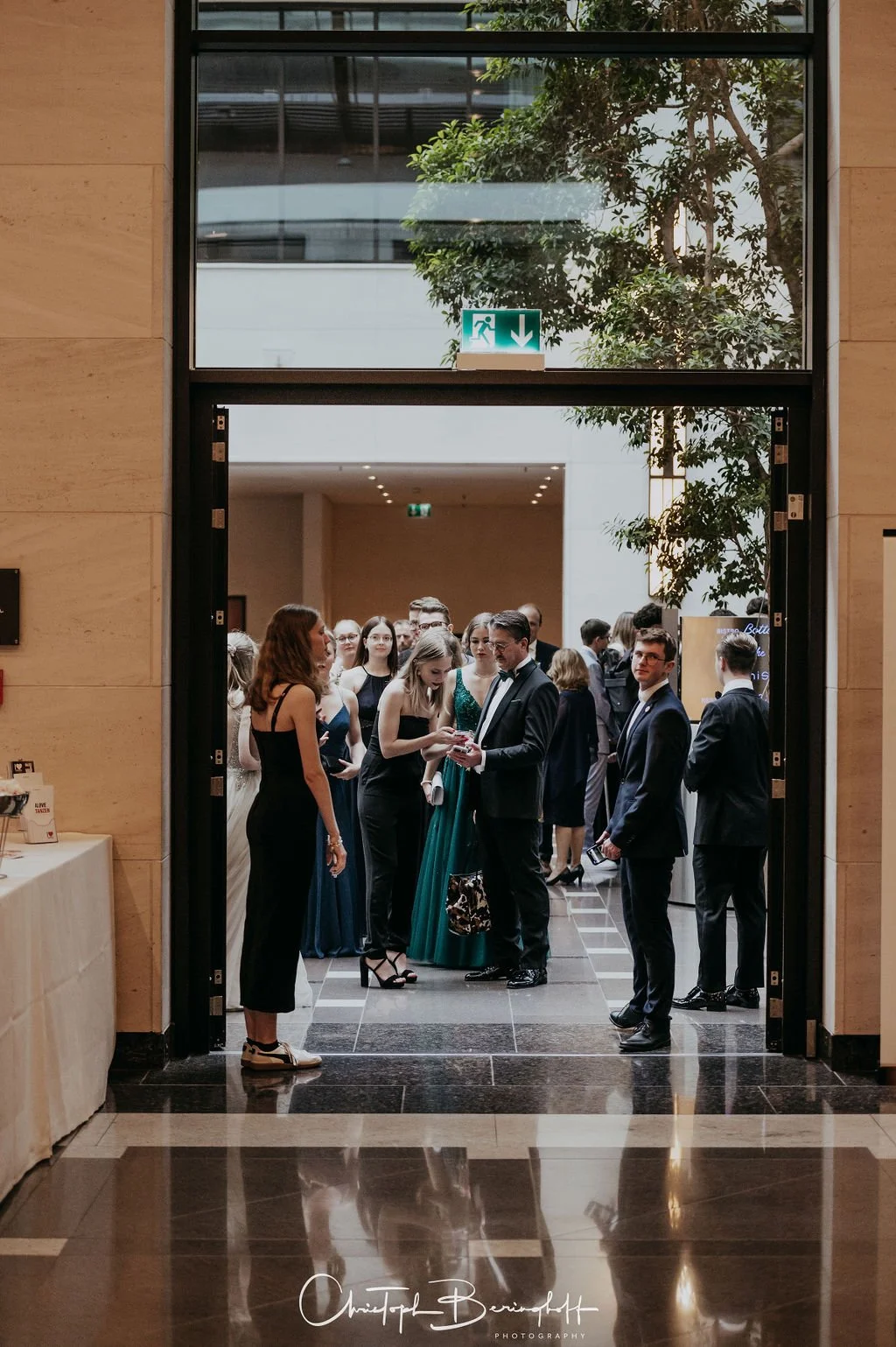 Menschen in formeller Kleidung stehen in einem Hotel-Lobby und unterhalten sich bei einer Veranstaltung.
