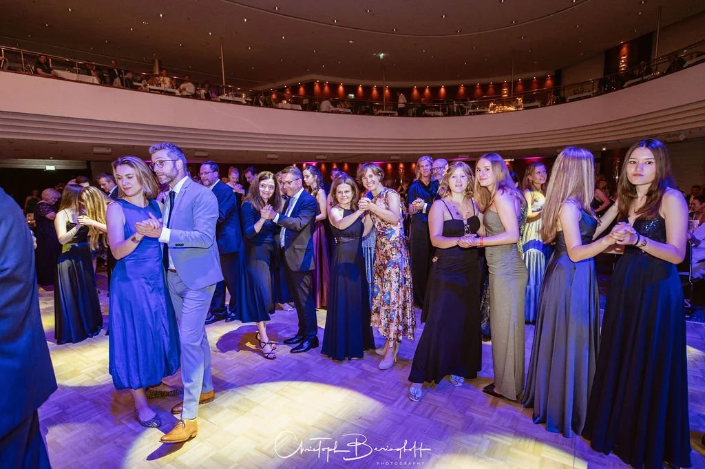 Menschen tanzen und feiern in einem eleganten Veranstaltungsraum.