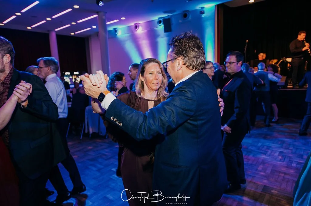 Menschen tanzen auf einer Party im eleganten Rahmen, bunte Beleuchtung, Live-Musik im Hintergrund