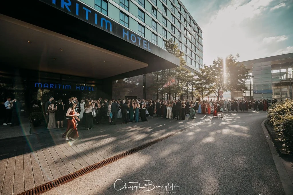 Menschen versammeln sich vor dem Maritim Hotel bei Sonnenuntergang.