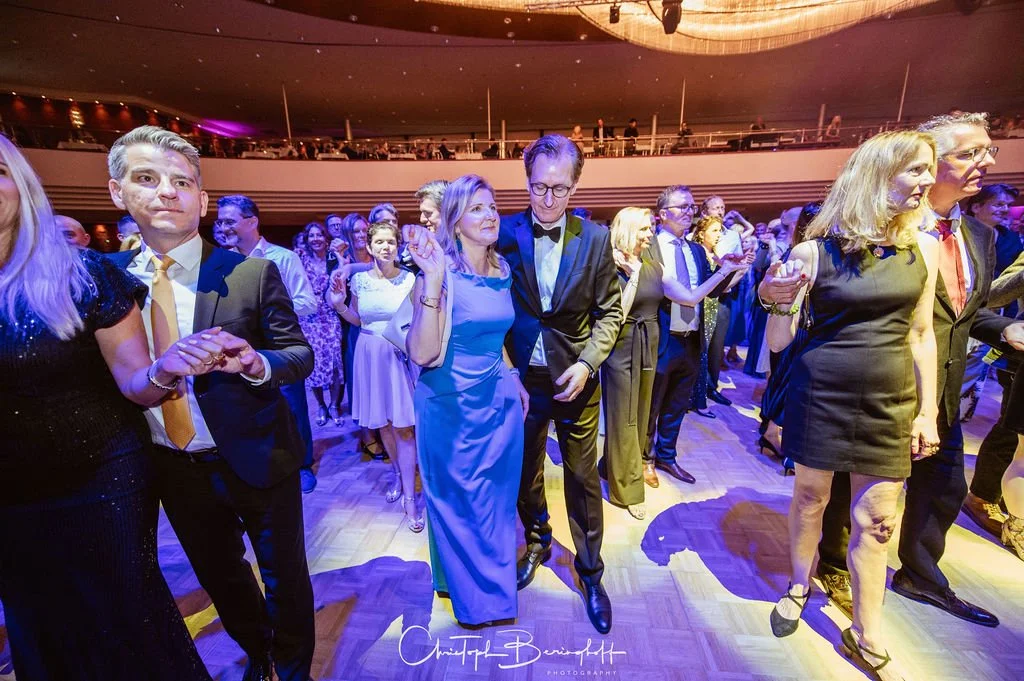 Menschen tanzen in eleganter Kleidung bei einer Veranstaltung.