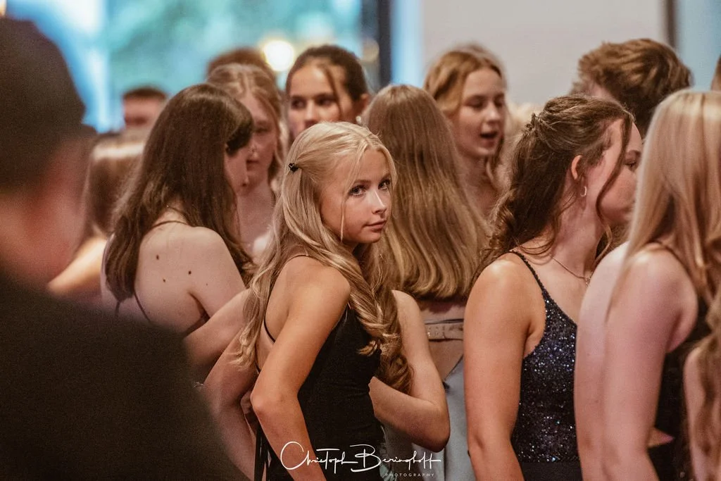 Mehrere junge Frauen auf einer Party, einige schauen in die Kamera, andere sprechen und lachen.