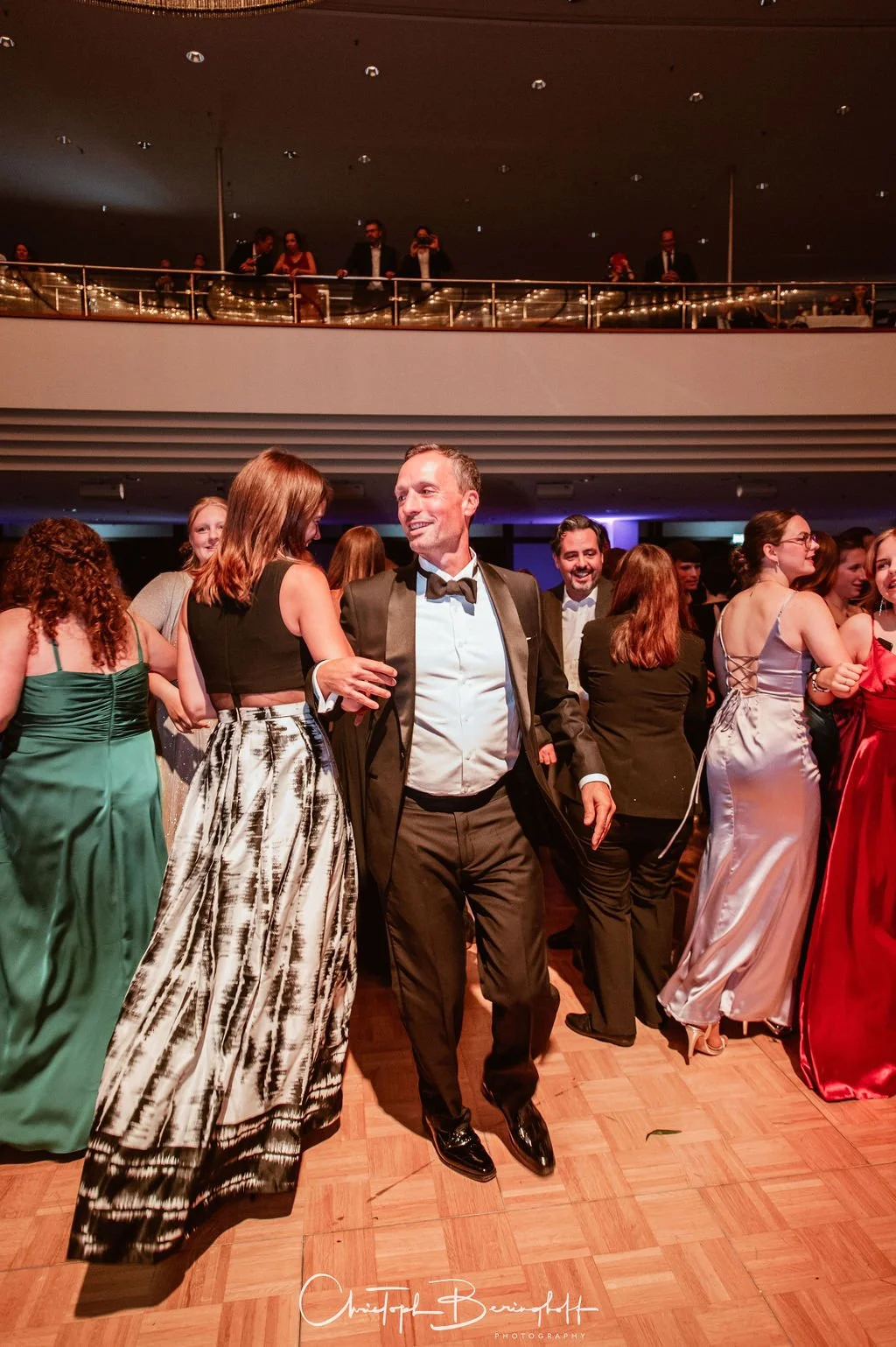 Menschen tanzen und feiern in festlicher Kleidung auf einem eleganten Veranstaltungsraum. Eindrucksvoller Anlass mit mehreren Gästen, die sich amüsieren.