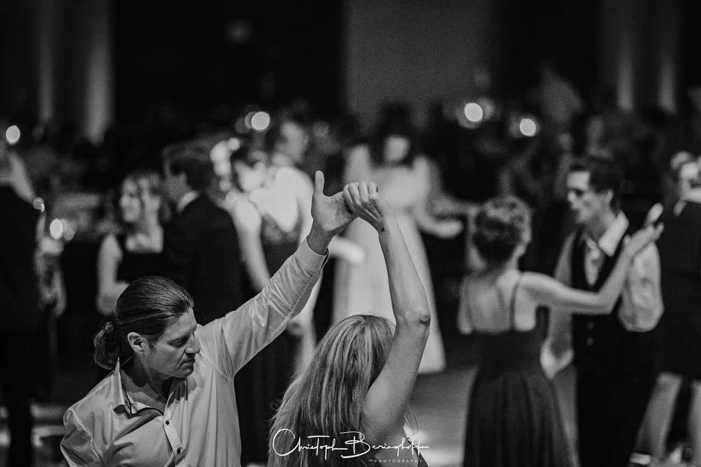 Paare tanzen auf einer schwarzen und weißen Hochzeit oder Party, während andere im Hintergrund ebenfalls tanzen.