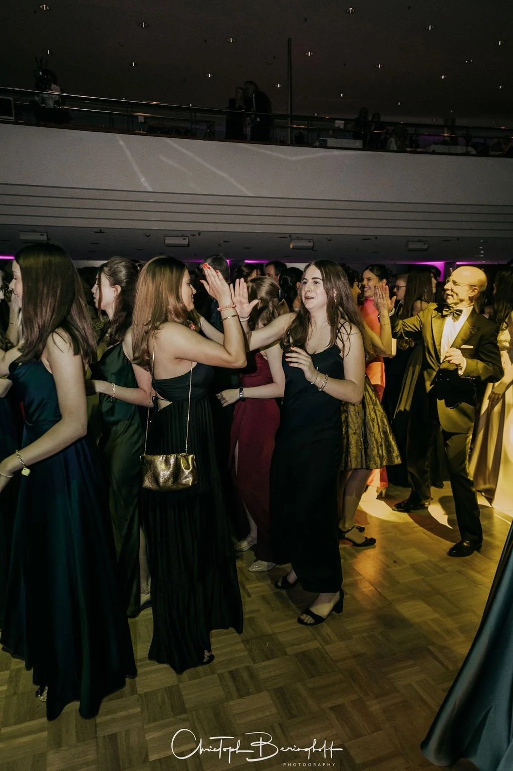 Menschen tanzen auf einer Gala-Veranstaltung, alle tragen elegante Abendkleidung im festlichen Ambiente.