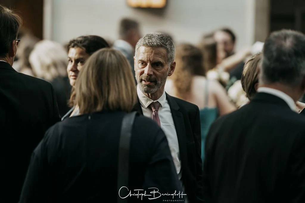 Menschen im eleganten Anzügen, die bei einer Veranstaltung Gespräche führen.