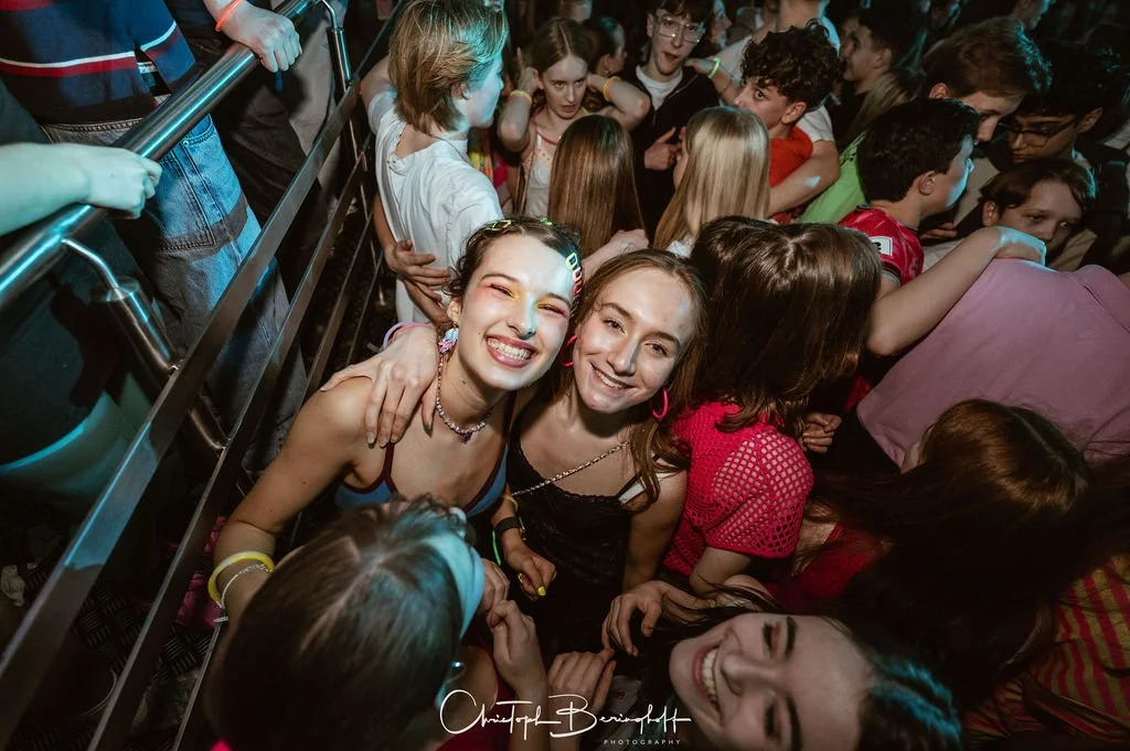 Many young people are partying, laughing, and dancing close together.