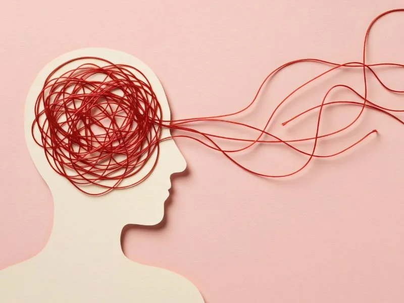 Conceptual illustration of a head silhouette with tangled red lines inside the brain area, representing mental health struggles