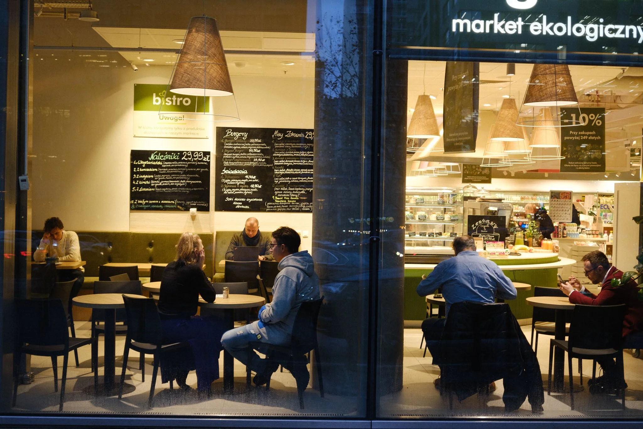 Street photo of Warsaw showing people in a cafe in the evening.