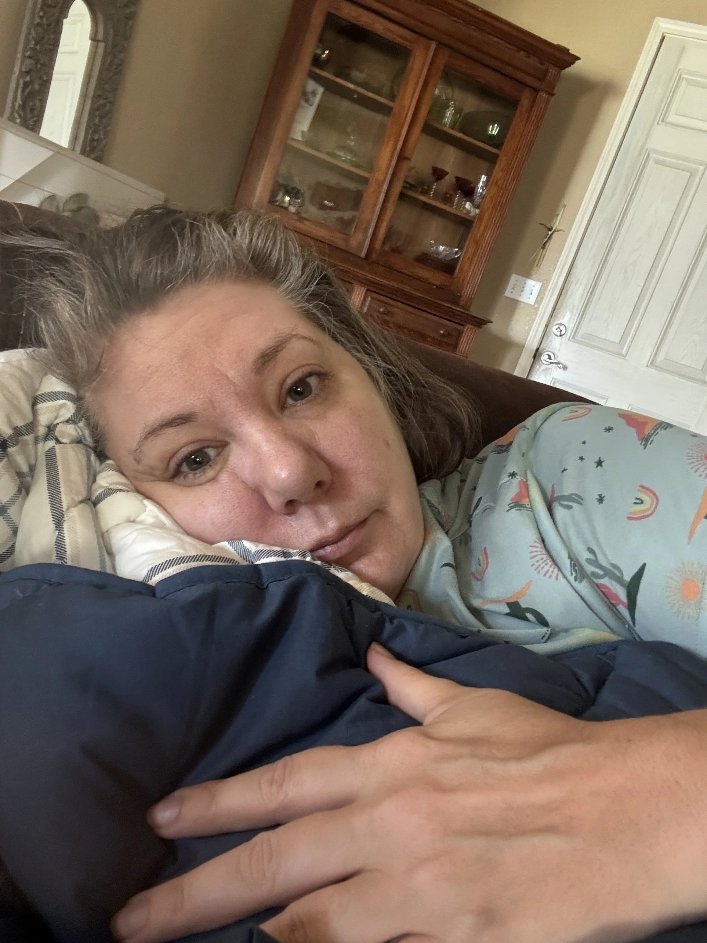 Caitlin, founder of Follow the Goose Travel, resting candidly on a pillow after months of family caregiving.