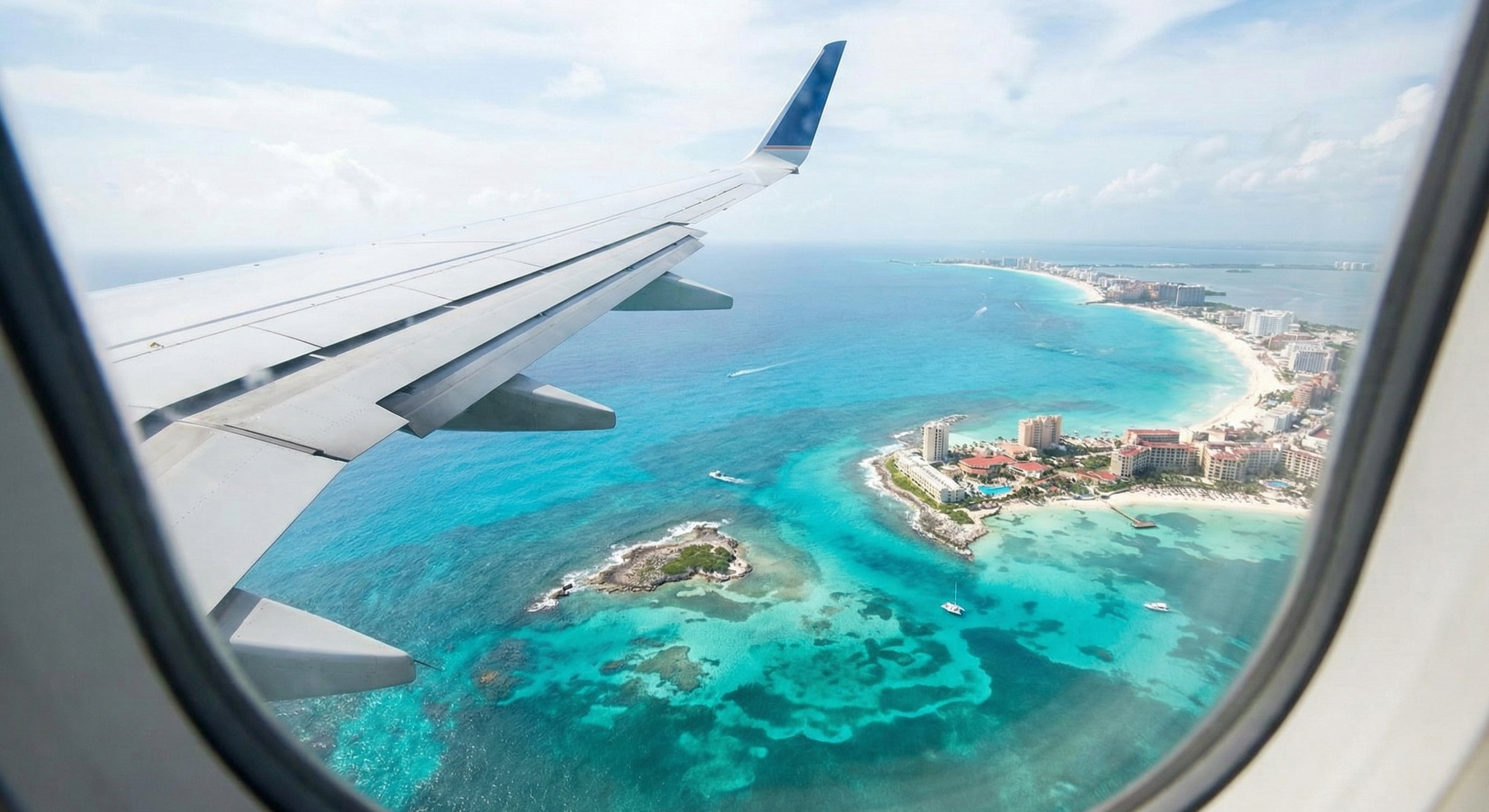 View from an airplane window looking down at the turquoise Caribbean coastline and islands, showcasing exclusive nonstop vacation flights from St. Louis to Cancun.