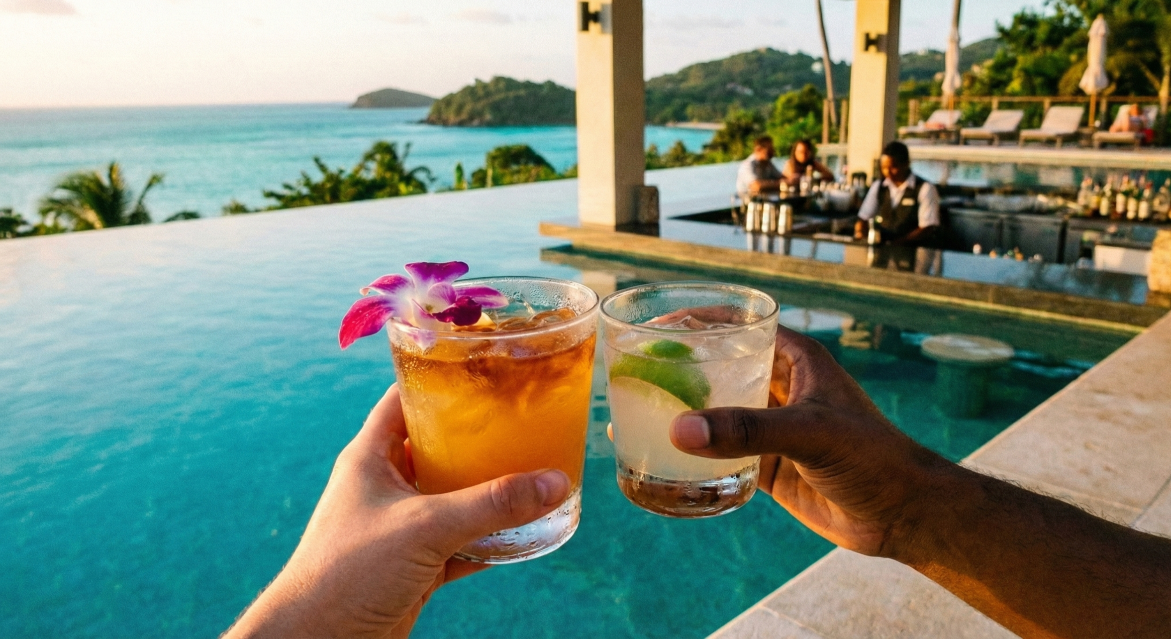 Close-up of two hands toasting tropical cocktails in front of a luxury infinity pool and lush green hills, highlighting a relaxing adults-only spring break getaway.