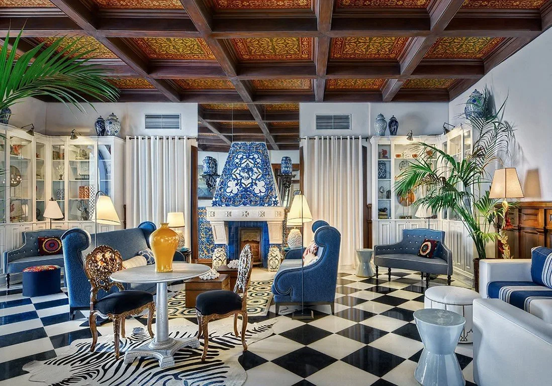 Eclectic and luxurious hotel lounge featuring blue velvet armchairs, black and white checkered floors, and intricate tile work, representing the high standards of a vetted Follow the Goose property.