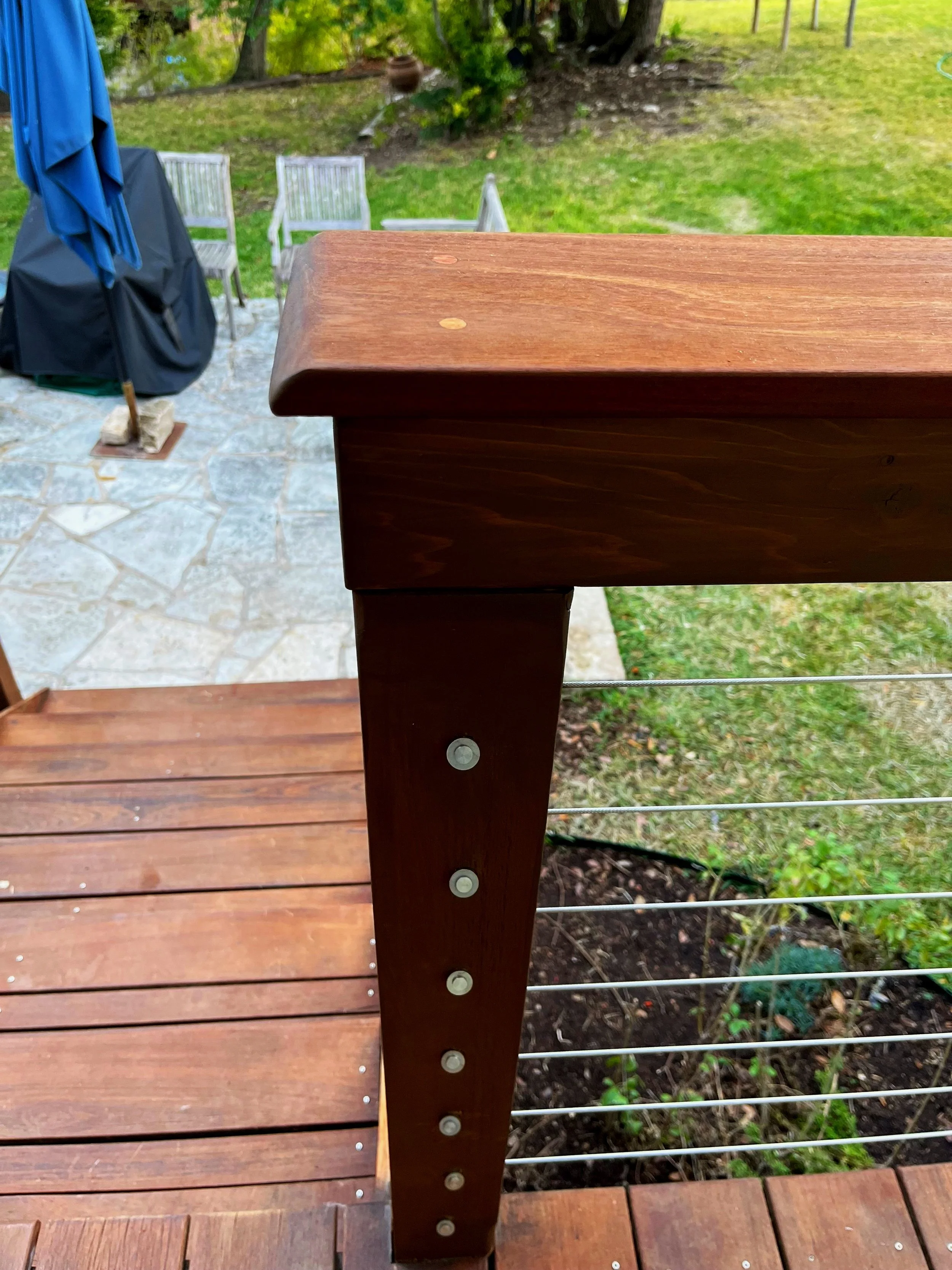 Seeking to modernize this backyard deck, we constructed a new railing with cedar posts and an Ipe railing cap with stainless steel cables.
