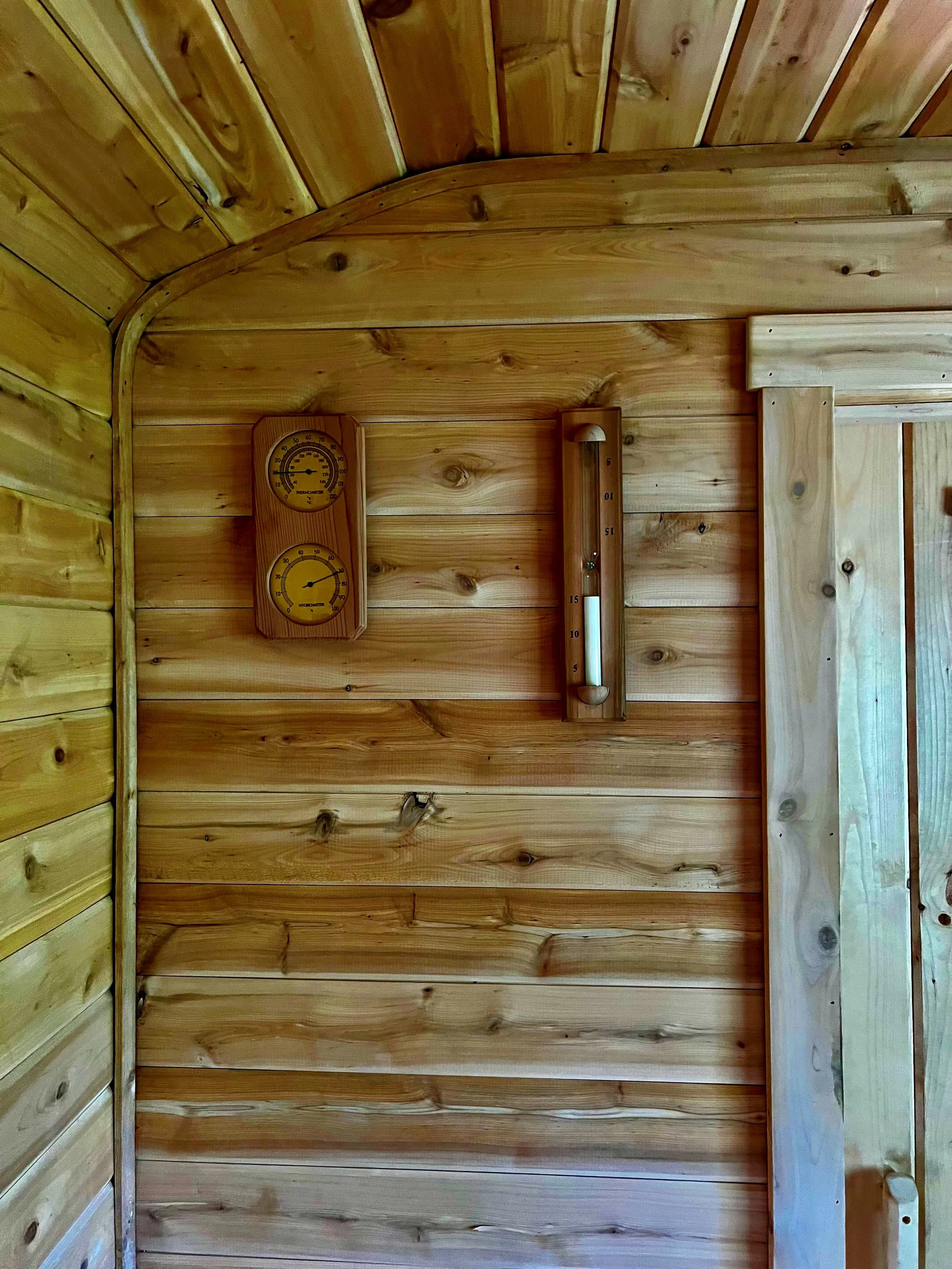 Wood-paneled wall with a thermometer, a hygrometer, and a hydrometer mounted on it.