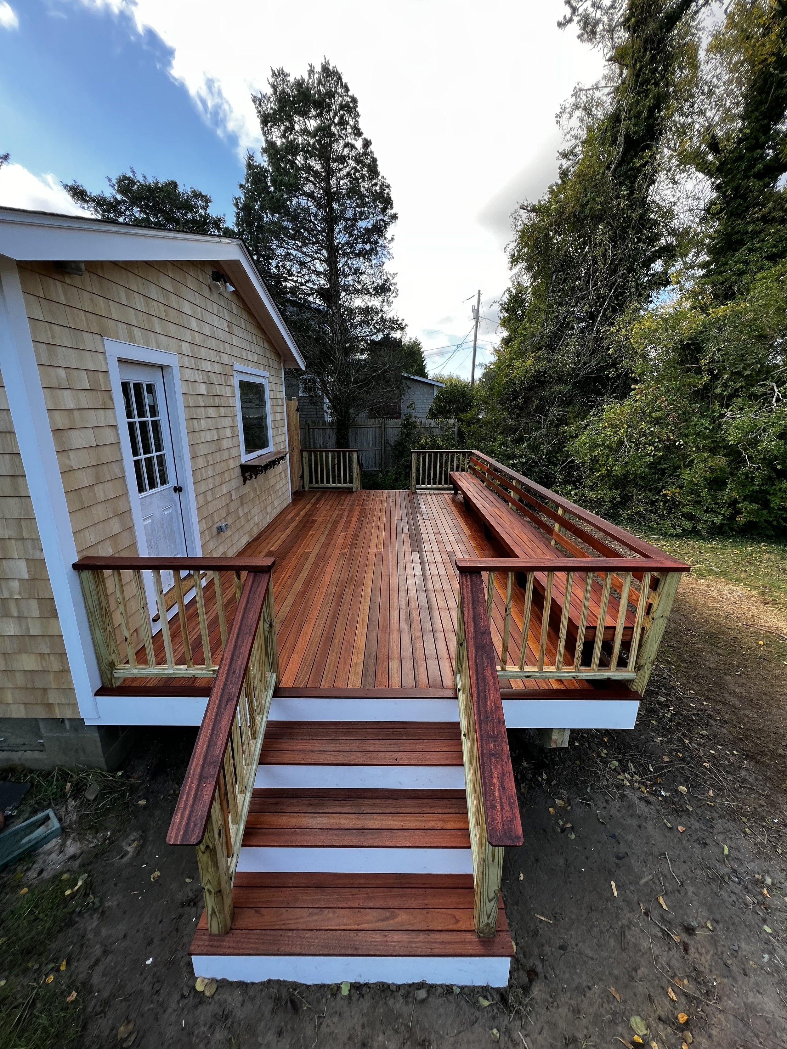 Featuring tropical mahogany decking and railing caps, matching white trim, two staircases and a built-in bench, this deck makes a great addition to this Martha’s Vineyard summer home.