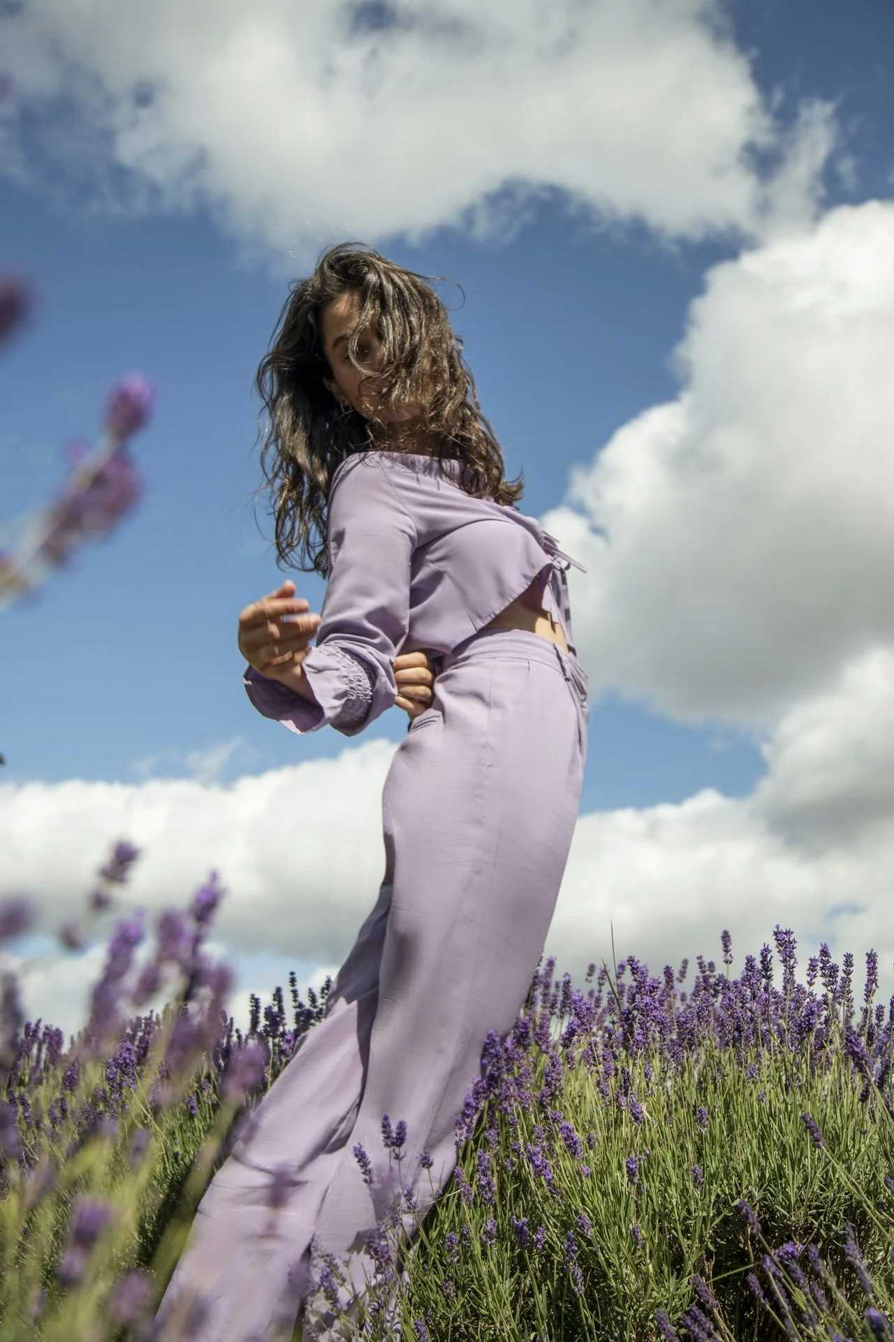 A woman moving freely in a lilac field on a sunny day.