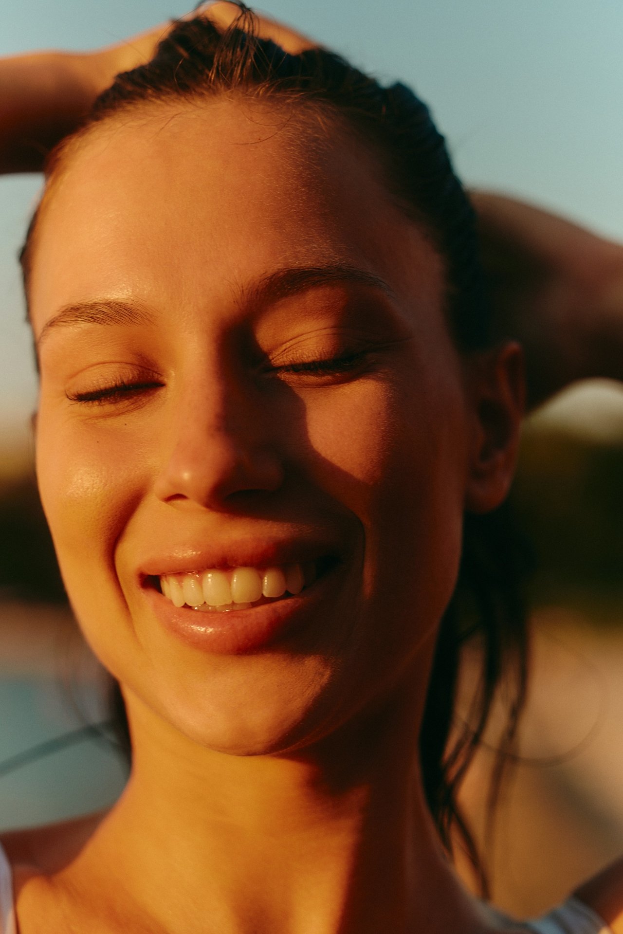 A close-up photo of a woman with her eyes closed, wearing a serene smile, radiating gratitude and inner peace from EMDR.