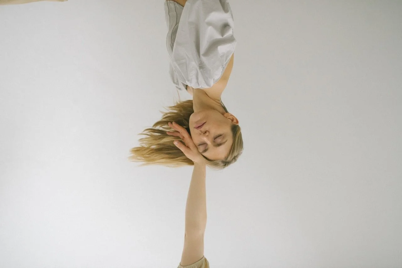 Upside down portrait of a calm woman with a hand gently touching her cheek, representing emotional integration in extended EMDR therapy.