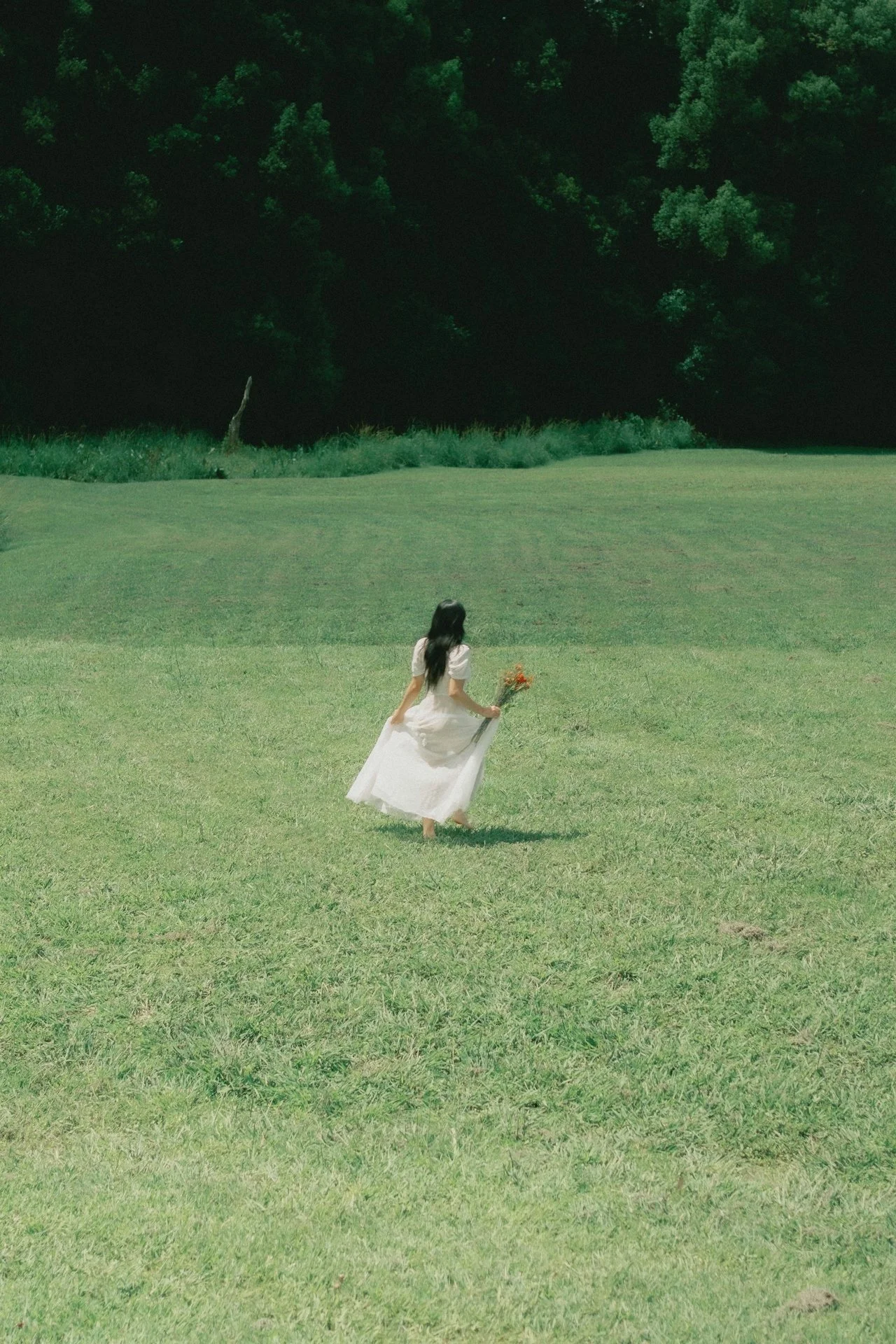 Woman walking barefoot in a peaceful natural landscape with flowers and sunlight, symbolizing emotional healing, calm, and reconnection with self.