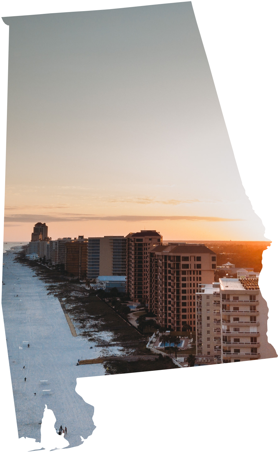 A beach town at sunset with high-rise buildings along the shoreline and a sandy beach in the foreground.