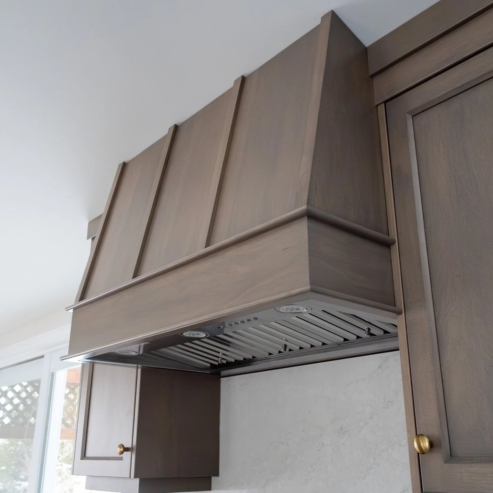 Close-up of a wooden kitchen cabinet with an under-cabinet range hood.