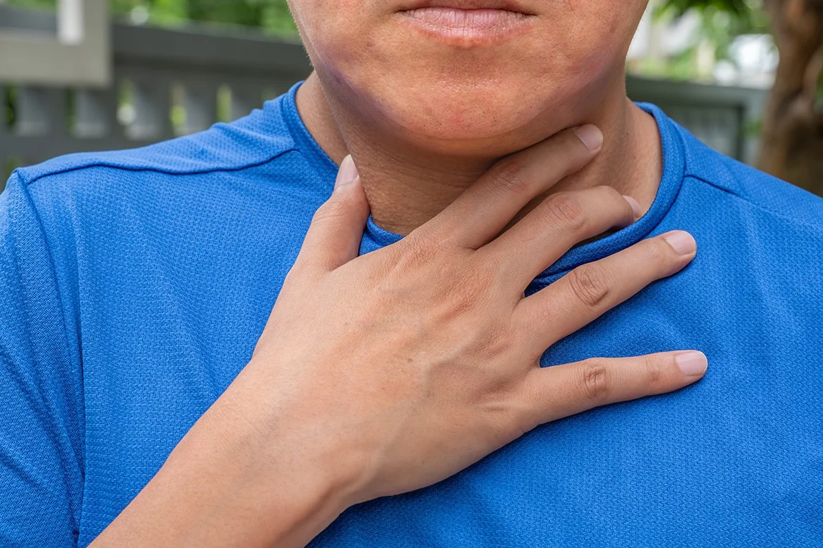A male individual holding onto his neck