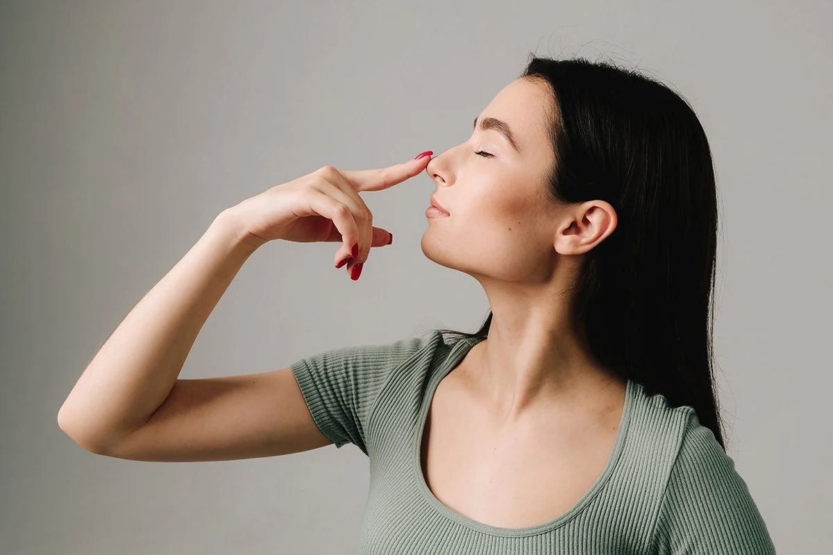 A young woman pointing at her nose